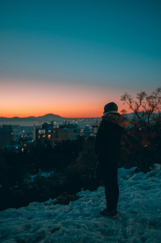 a person is standing in the snow at sunset