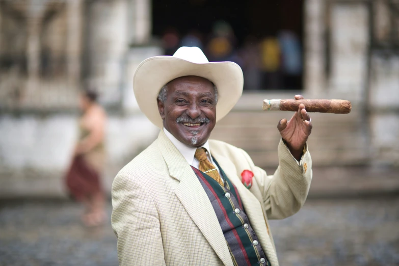 an old man in a straw hat holding up a cigar