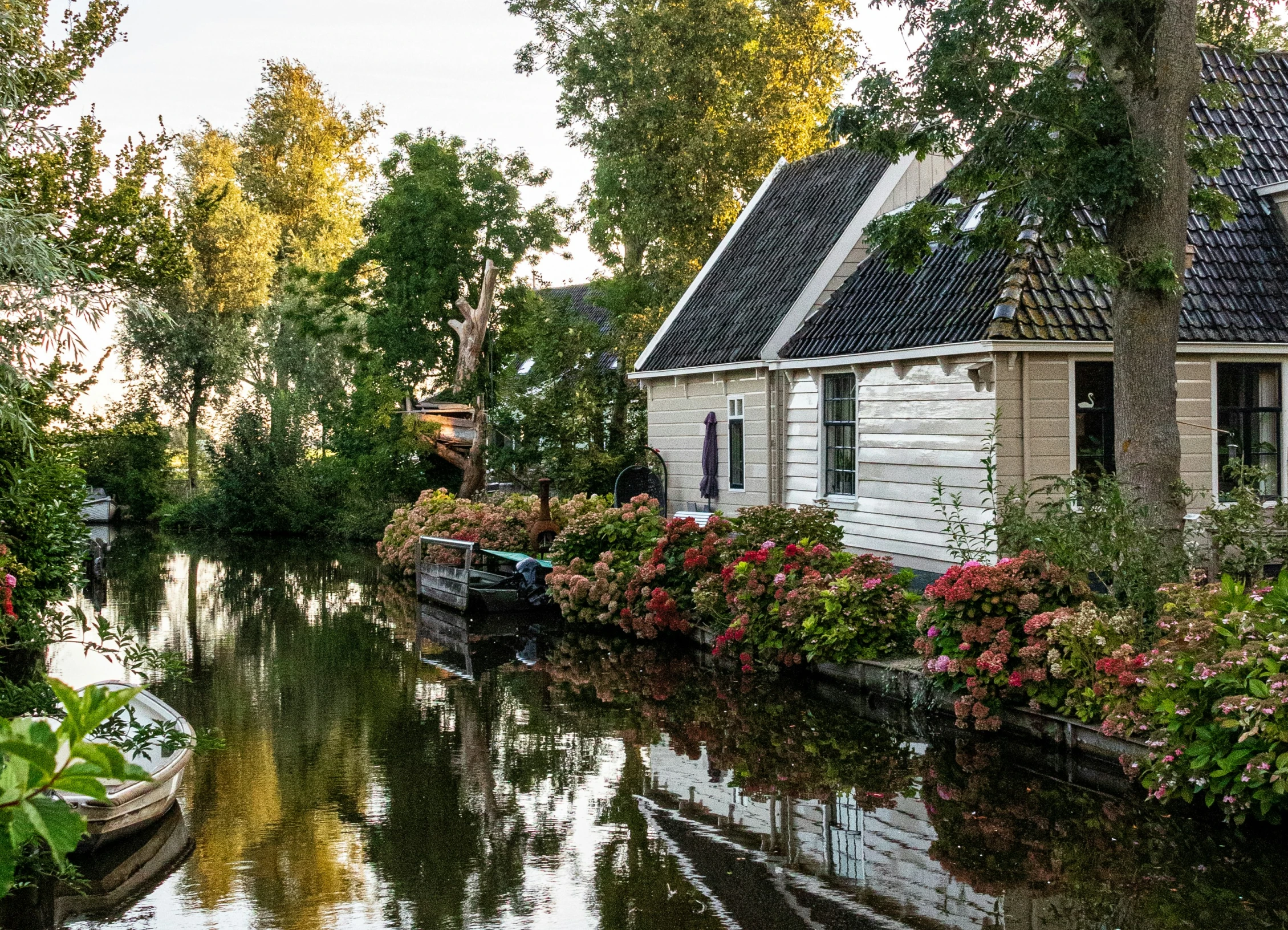 house along side waterway in urban area with trees and flowers