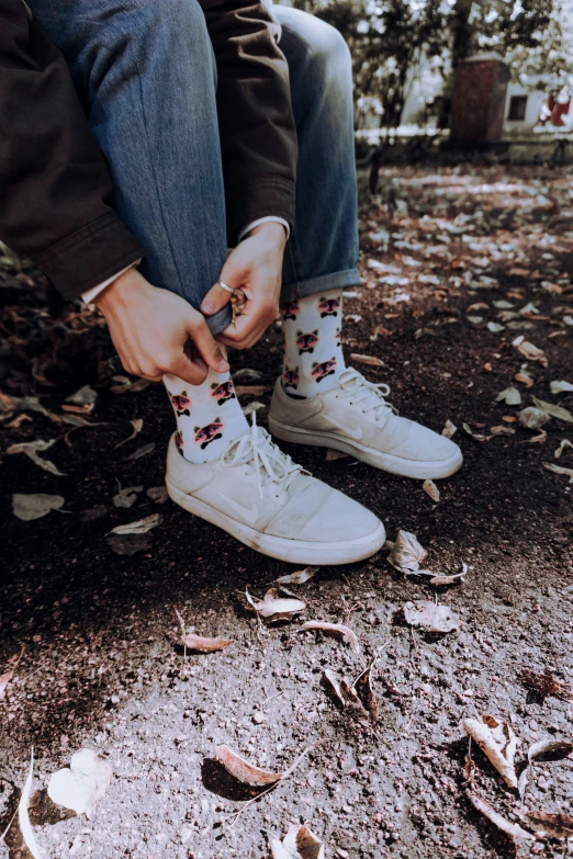 the person is tying the shoelace to her tennis shoes