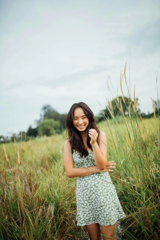 a woman smiling and standing in tall grass