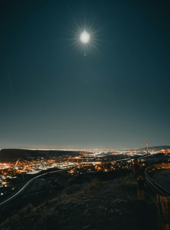 the moon above a city as seen from a hill