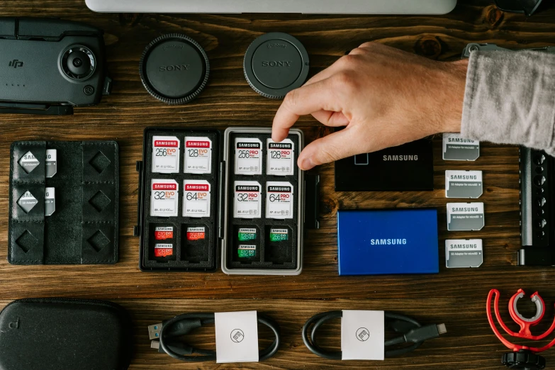 a person's hands are over the many electronics laid out on a table