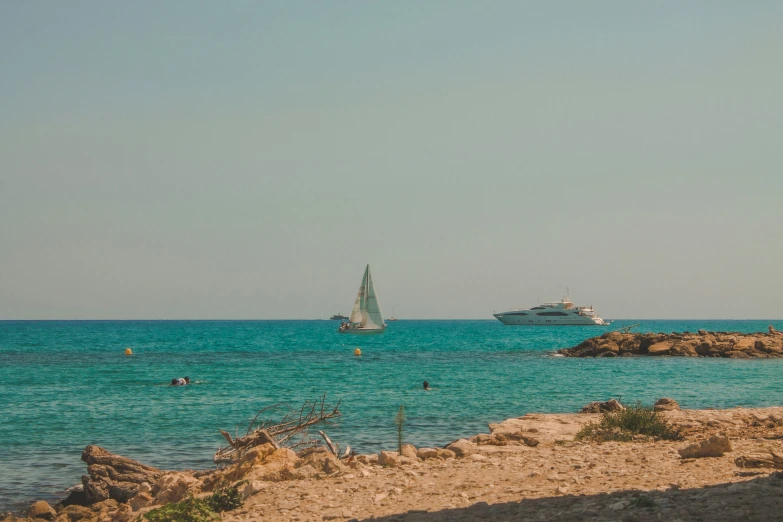 people standing on the shore by boats near the sea