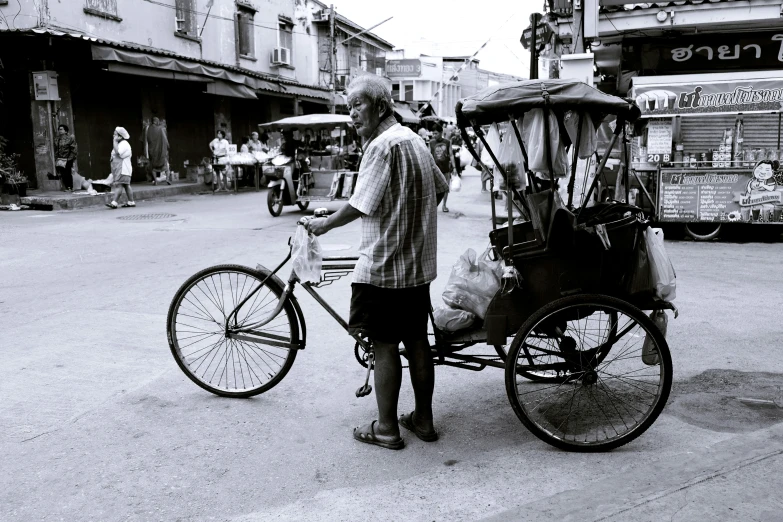 a man standing by a parked bike in the middle of a street