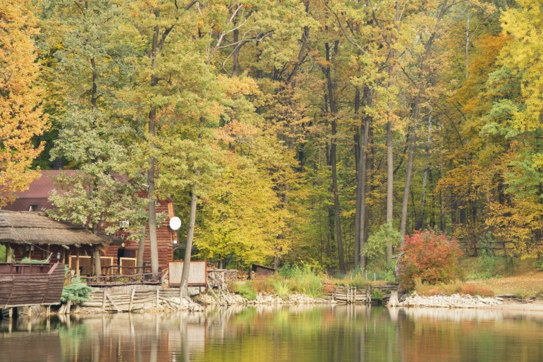 a cabin is sitting by the water surrounded by trees