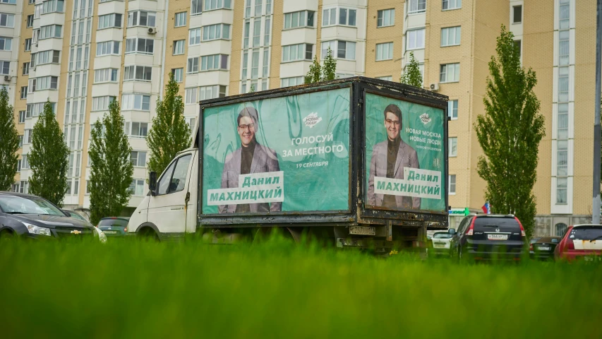 a truck is driving past tall buildings with signs on the side