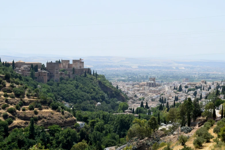 a city with hills, trees and grass in the foreground