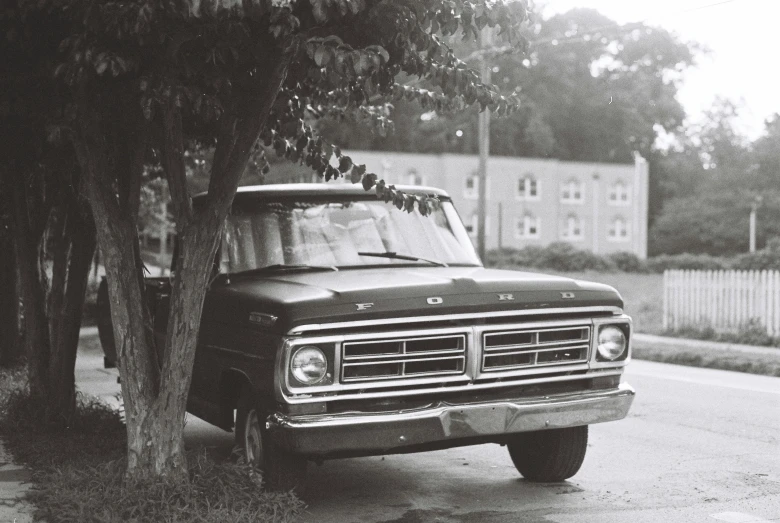 an old truck is parked along side a tree