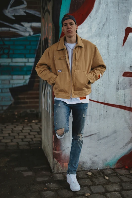 a man is posing next to a wall