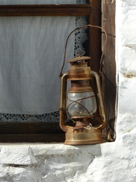 the old rusty lamp is sitting beside the window