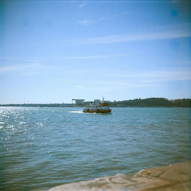 a small boat out in the ocean with a bridge in the background