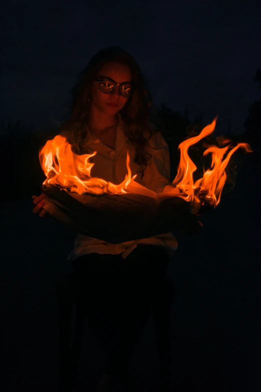 a woman sitting down holding some orange fire