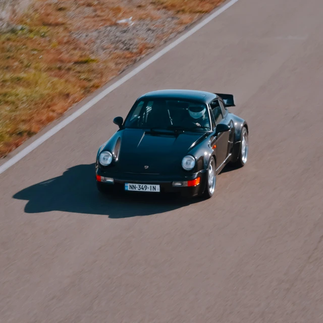 a sports car with the roof down driving on a winding street