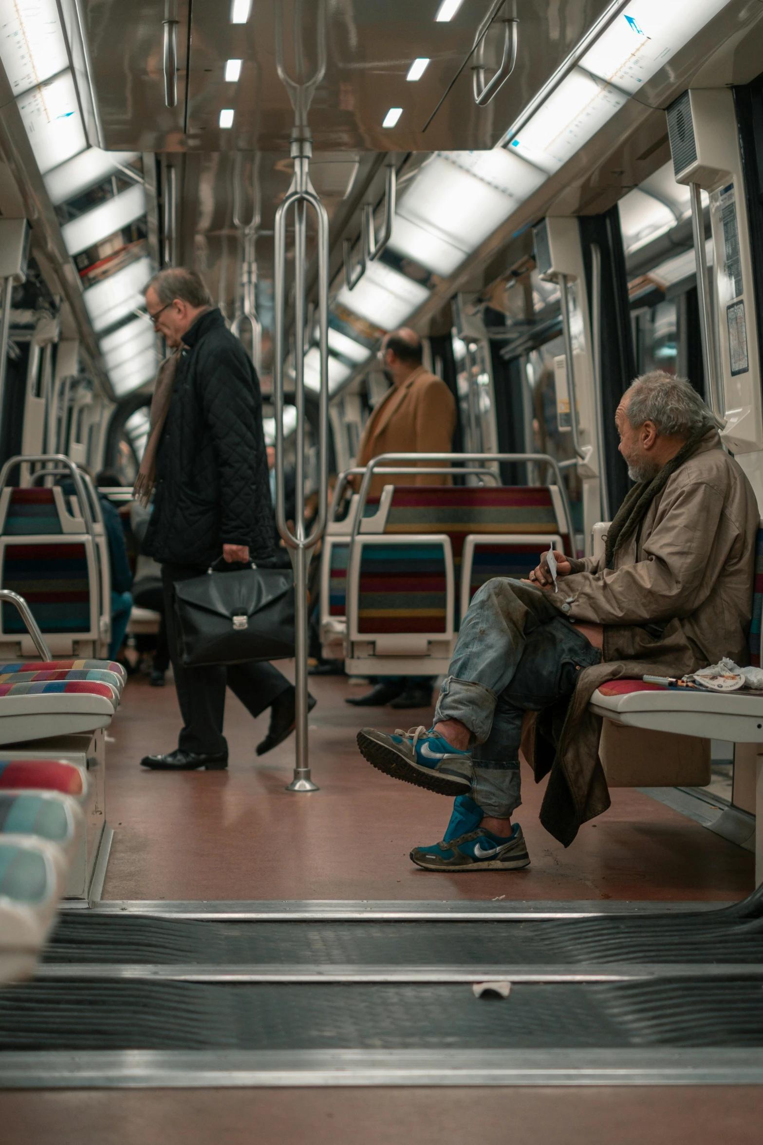 two men sitting on a train on their phones