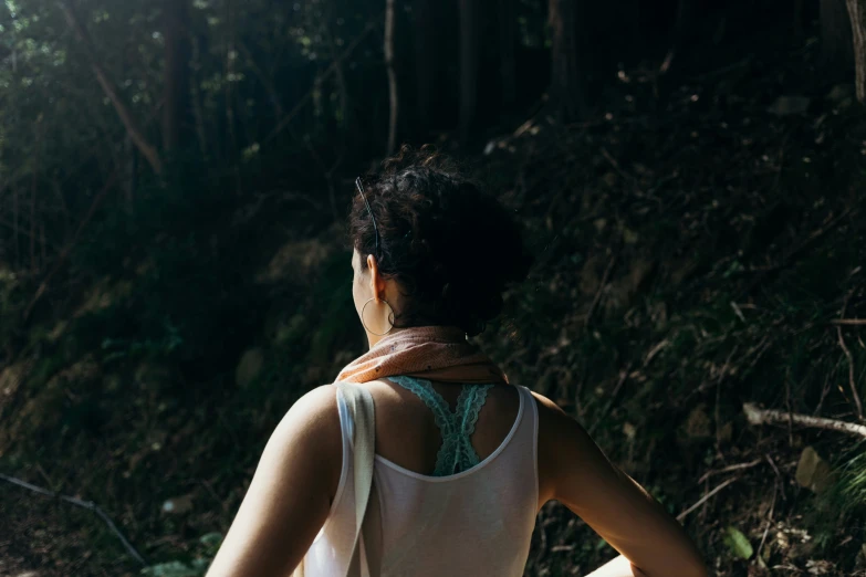 a woman wearing white is walking in the woods