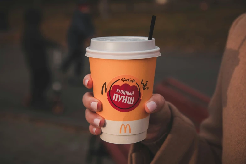 a person holding up a take out coffee cup