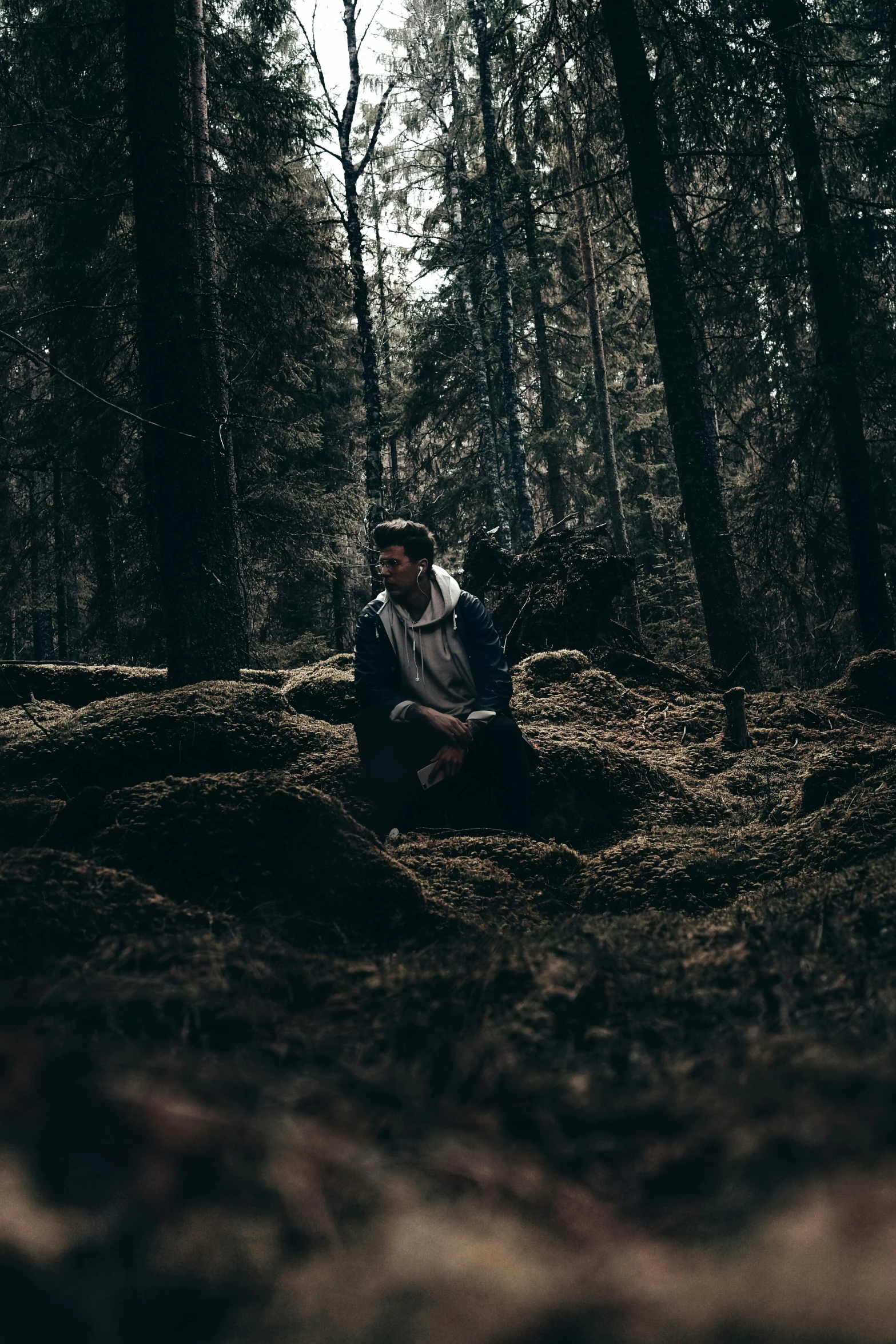 a man sitting in the woods near some trees
