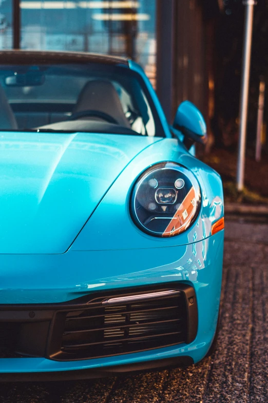 the front end of a blue car parked in front of a building