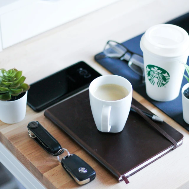 some cups and two phones with a key on a table