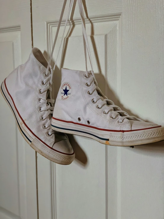 converse converse sneakers hanging from a door