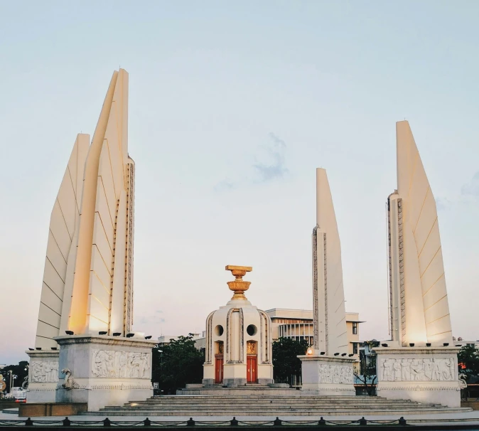 a monument with large pillars surrounding it near a building