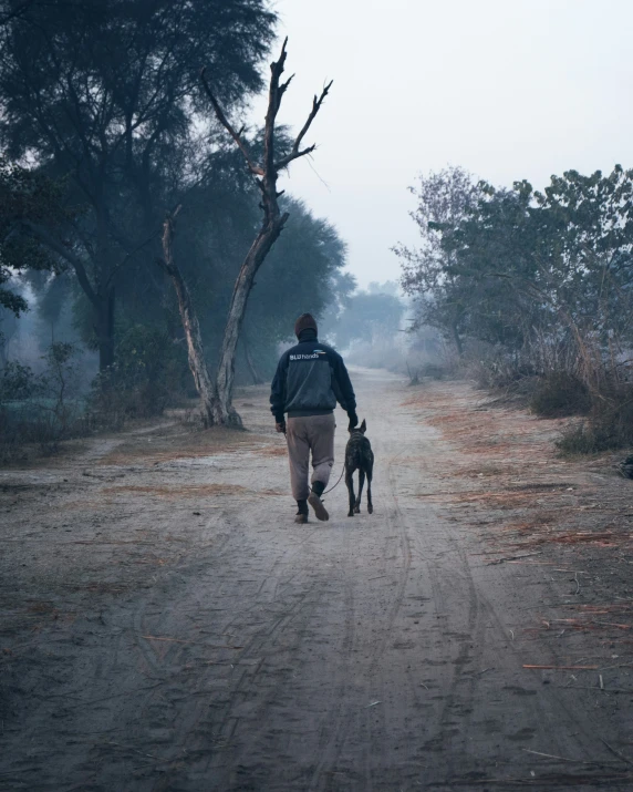 a man is walking with his dog in the rain