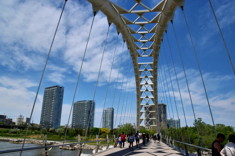 people walk across a tall bridge above water