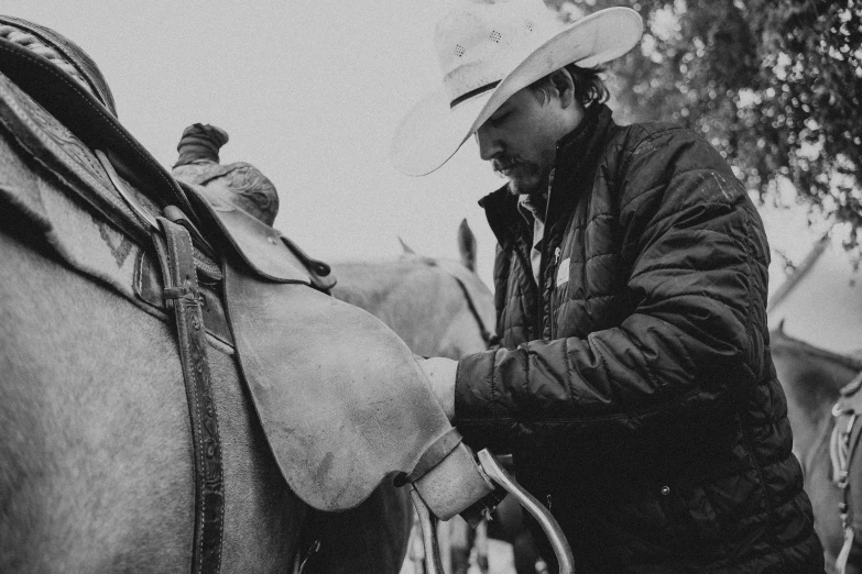 a man wearing a hat petting a horse