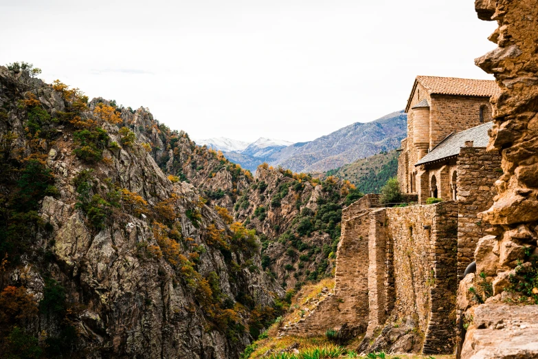 a stone building on the side of a mountain cliff