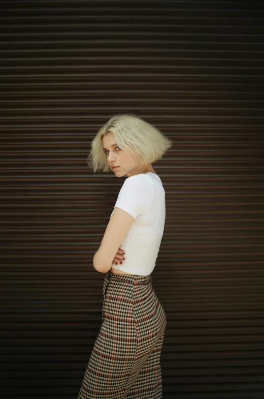 a blond woman standing in front of a striped wall