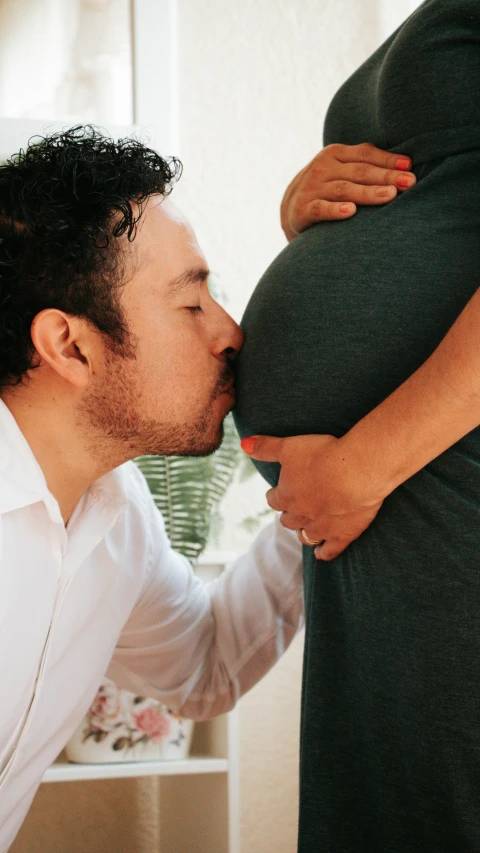 a man kissing a pregnant woman on the cheek