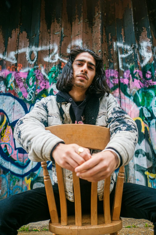 a man sitting in a wooden chair with his hands on the chair