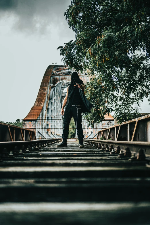 a person standing on train tracks near trees