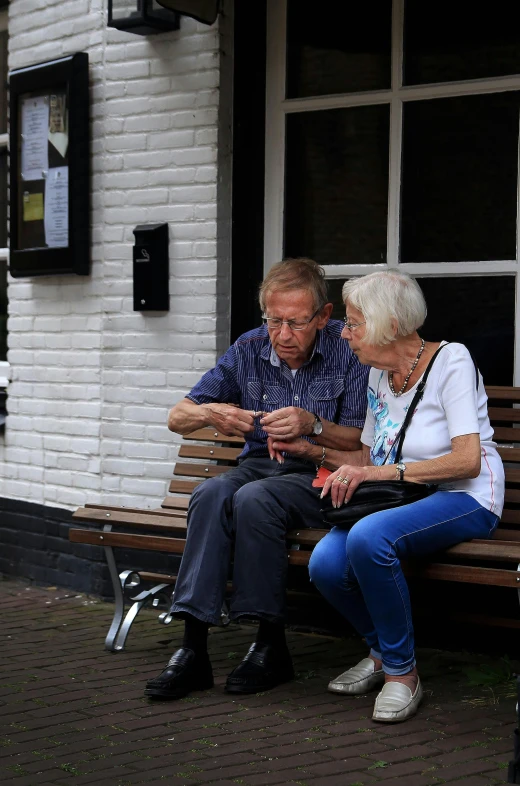 two elderly people sitting on a wooden bench