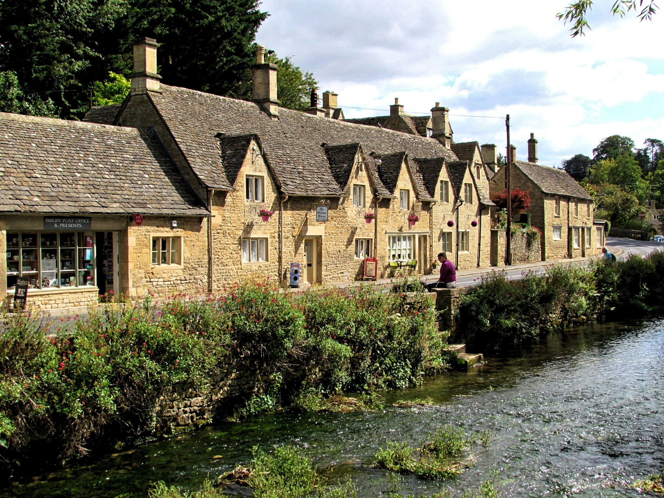 old brick buildings along the river by some bushes