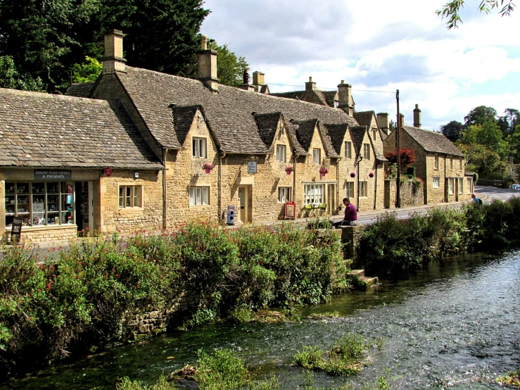 old brick buildings along the river by some bushes