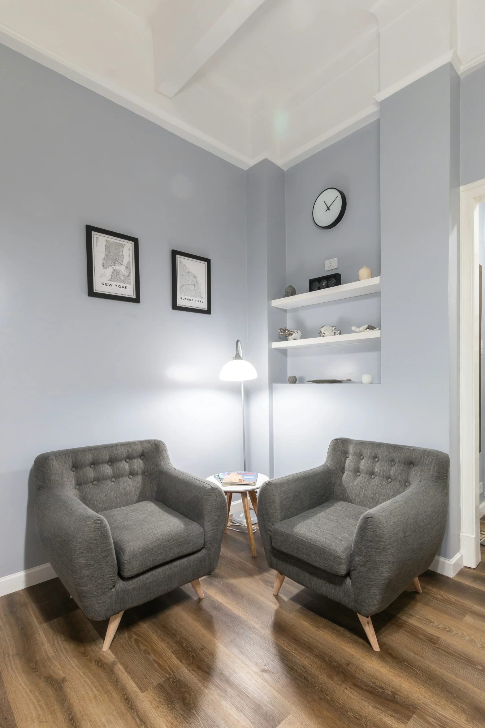 two gray couches in an empty room with a clock on the wall