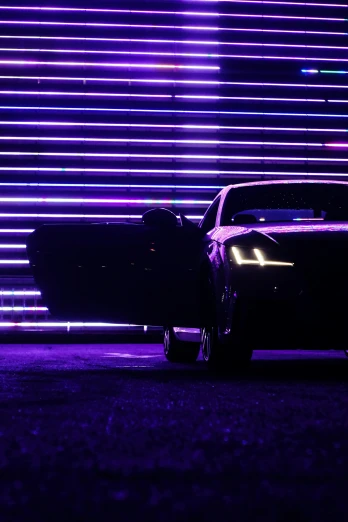 the front and back end of a black car in front of colorful lights