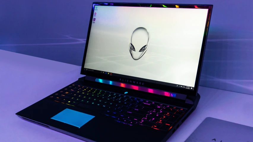 a laptop computer on a table with an alien head on it