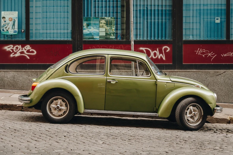 a green car parked in front of a building with graffiti