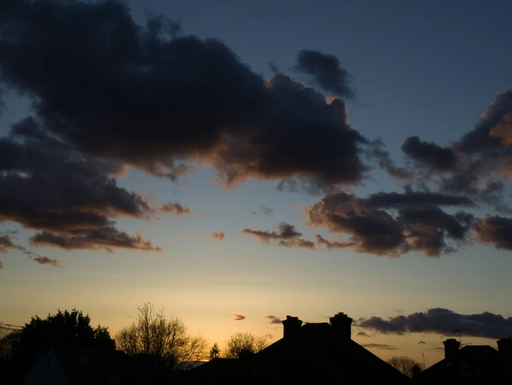 the sun rises over houses and clouds