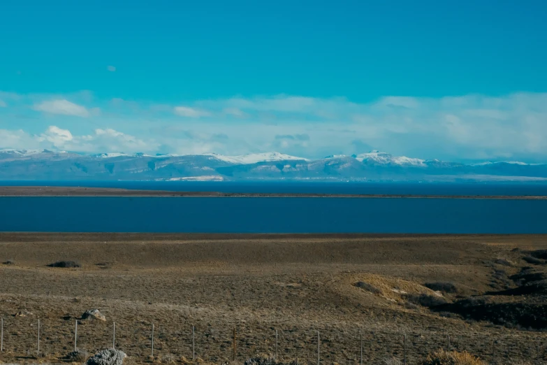 there is a large field that has blue sky and snow capped mountains