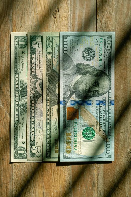 three bills of one hundred dollars are shown with a small brown object between them