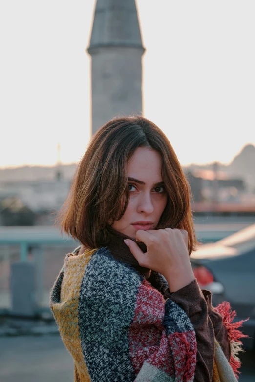 a young woman leans against a metal fence and stares off into the distance