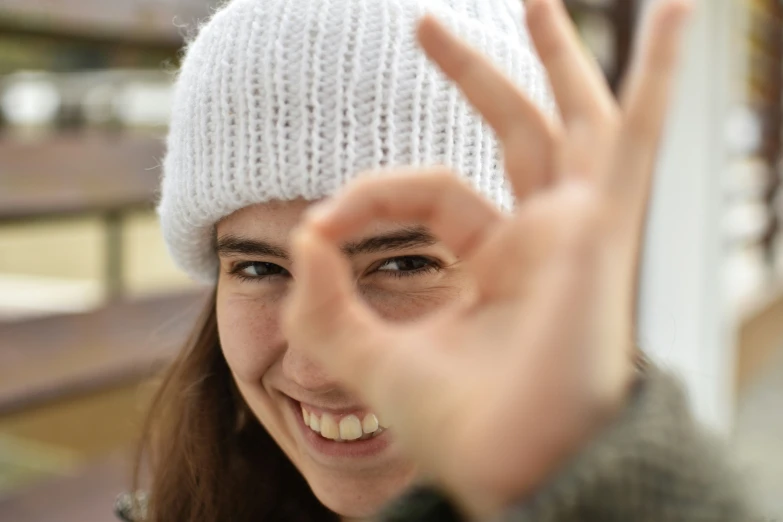 a girl in a knit hat is making the middle sign