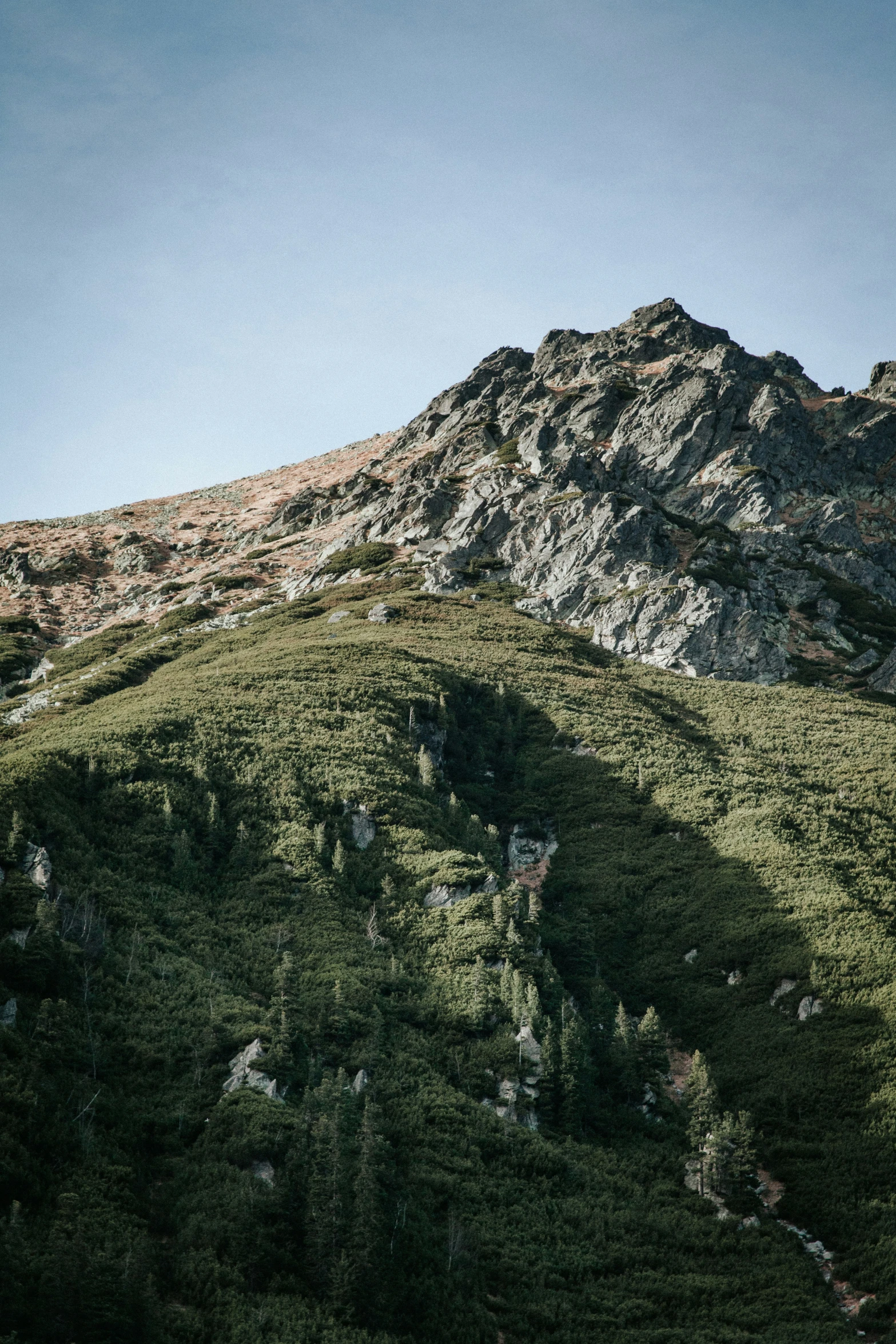 a rocky mountain side with a clear blue sky above