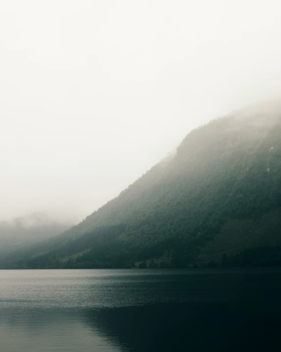 mountain lake on cloudy day with trees in the mist