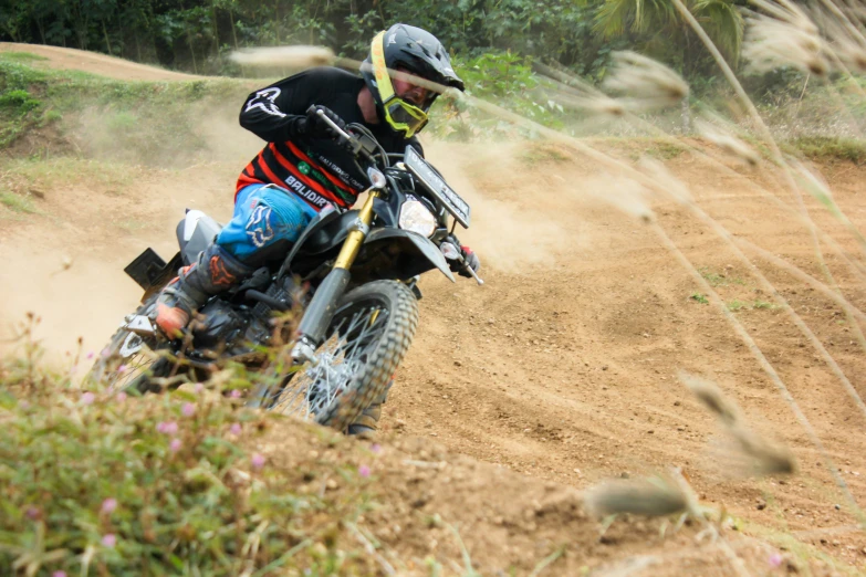 a man riding on the back of a motorcycle on top of a dirt field