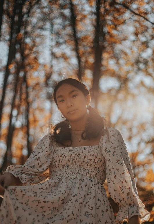 a young woman is posing near some trees